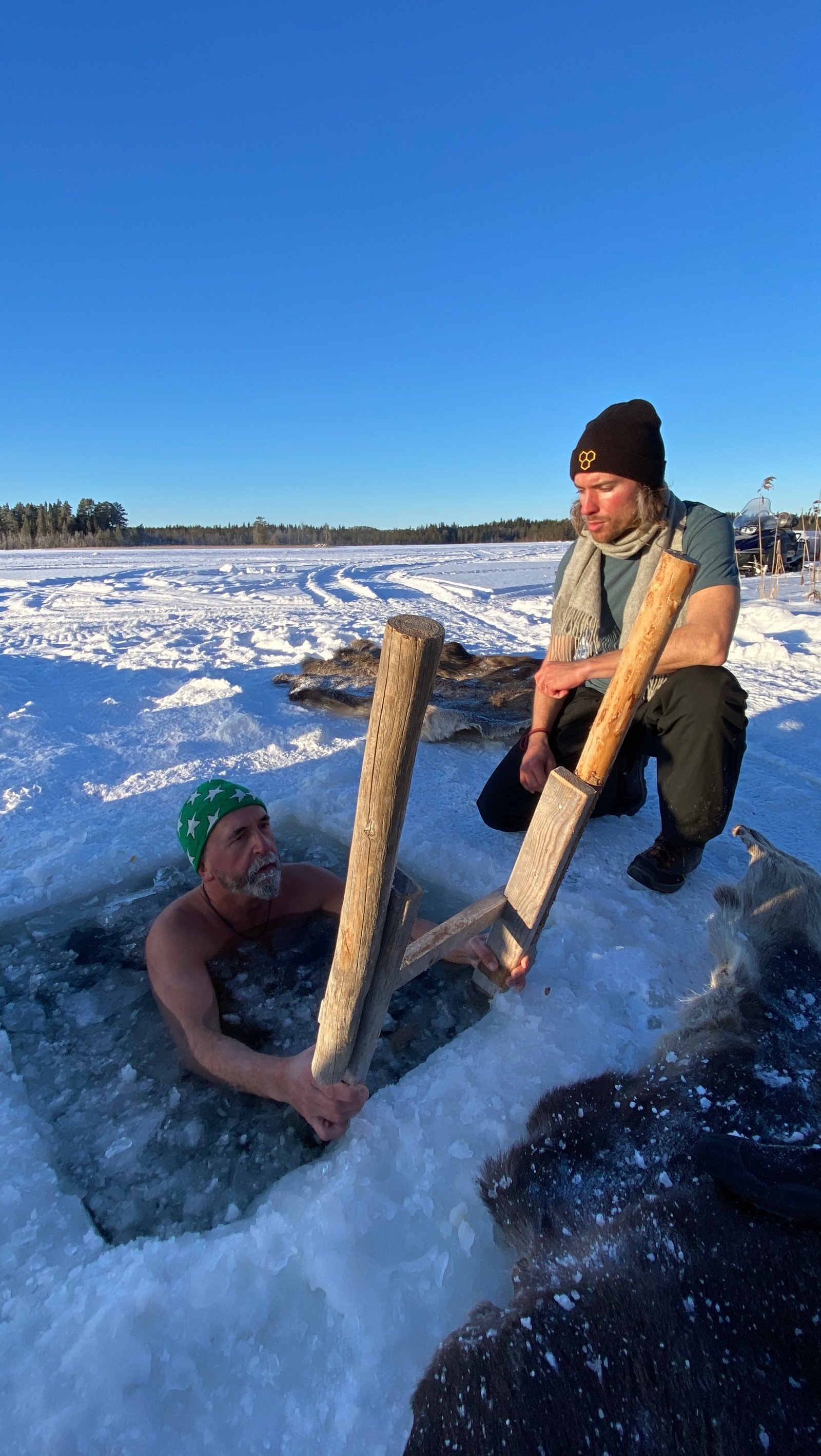Filip guiding a participant during an ice bath in a frozen Swedish lake